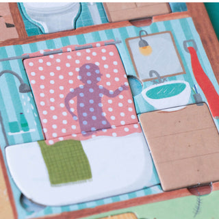 A close-up of a colorful children's game featuring illustrated bathroom scenes, including a pink polka-dot bathtub, a white sink, a mirror, and a brown cardboard piece.