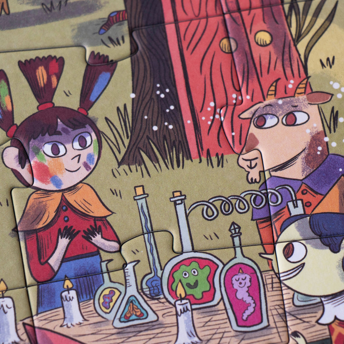 A close-up of a colorful illustrated puzzle featuring cartoon characters and scientific props, including bottles, candles, and a tree in a whimsical scene.