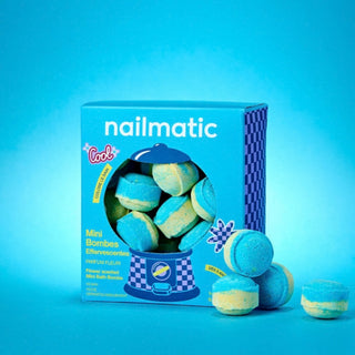 Nailmatic Mini Bath Bombsin their box, with several round blue and pale yellow bath bombs displayed in front on a bright blue background.