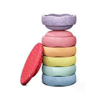 A set of six pastel-colored, textured Original Staplestein pieces stacked vertically, with a red speckled board piece leaning against the stack on the left. The top piece is lavender with multicolor speckles, and the stacked pieces below are pink, orange, green, mint, and light blue.