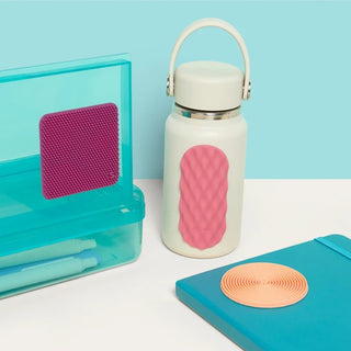 White water bottle with pink textured grip, turquoise case, and blue notebook on a light blue background
